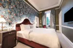 Luxurious king bed in Roxburghe Hotel suite with floral wallpaper and high-grade furnishings.