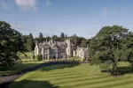 Large stone mansion with a lush lawn and trees at Roxburghe Hotel Golf & Spa Ltd.