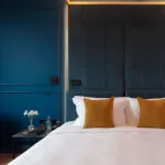 Elegant bedroom at 12.18. Roxburghe Hotel Golf & Spa with luxurious bedding and serene blue wall, ideal for relaxation.