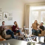 Group of people relaxing on couches in elegantly furnished living room, capturing the essence of comfort and style at 12.18. Roxburghe Hotel.