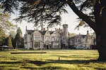 Historic Roxburghe Hotel estate with lush lawn and trees under a clear sky