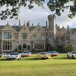 Cars parked on a lawn at Roxburghe Hotel with Floors Castle in the background, Scottish Borders.