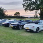 Luxury and sports cars parked on grass at Roxburghe Hotel, perfect for car enthusiasts.