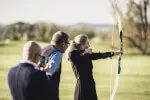 Woman practicing target archery outdoors on a grassy field