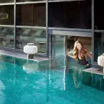 Woman in jade green heated infinity pool at Roxburghe Hotel Golf & Spa, illuminated by LEDs