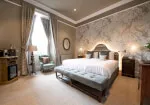 A cozy bedroom with bed and bench at 12.18. Roxburghe Hotel Golf & Spa Ltd.