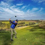 A golfer swinging a club on the lush greens of Roxburghe Hotel Golf & Spa Ltd.