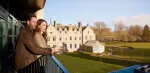 Woman enjoying a glass of wine on a balcony at Roxburghe Hotel with a view, celebrating the 'Third Night Free' offer.