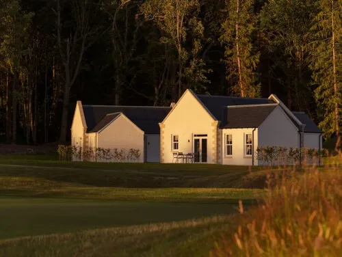 Elegant buildings at Roxburghe Hotel Golf & Spa amidst lush greenery.