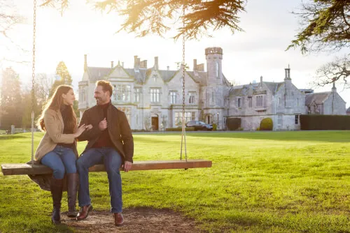 A couple on a swing at Roxburghe Hotel Golf & Spa, with the historic building in the background.