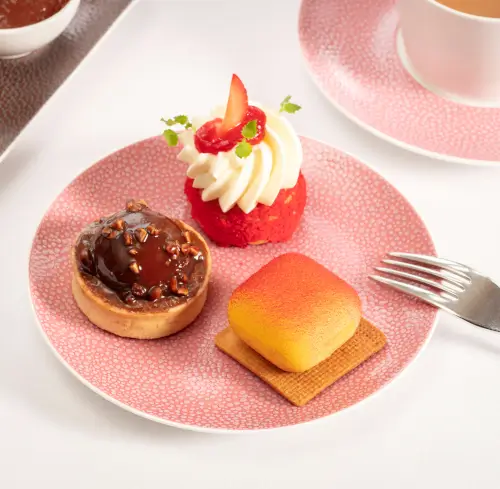 Decadent festive afternoon tea sweets including a chocolate tart and red cake with strawberry.