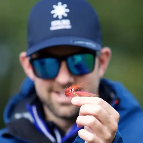 A person at Roxburghe Hotel Golf & Spa holding a bright fishing lure outdoors.