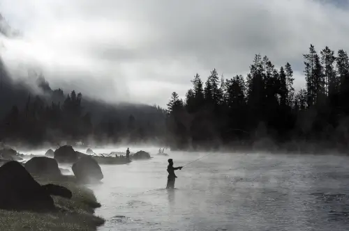 A tranquil fishing scene at Roxburghe Hotel Golf & Spa with misty river and trees.