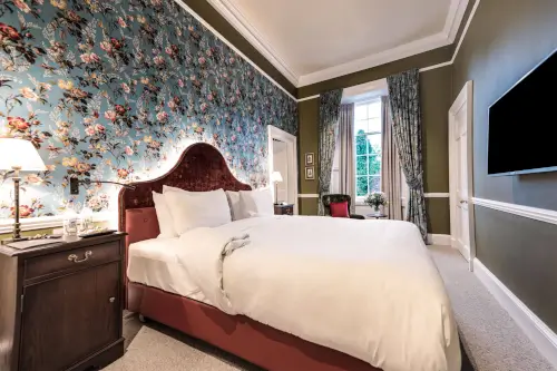 Luxurious hotel room at Roxburghe Hotel with elegant decor and floral wallpaper.