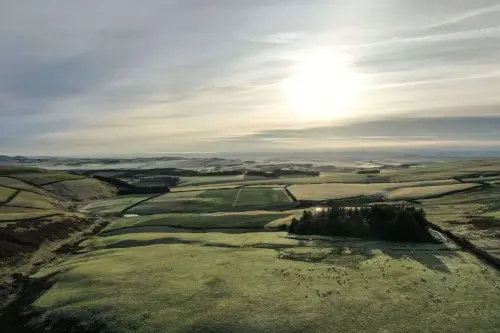 Scenic landscape view showing rolling hills and a sunlit sky.