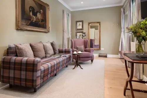 Elegant lounge at Roxburghe Hotel featuring a plaid sofa and a purple armchair.