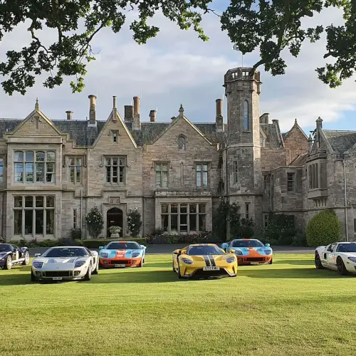 Historic Roxburghe Hotel with luxury sports cars in the foreground, showcasing elegance and luxury.