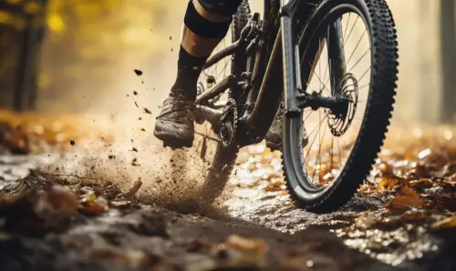 A mountain biker rides through muddy terrain covered with autumn leaves at the Country Sports Centre.