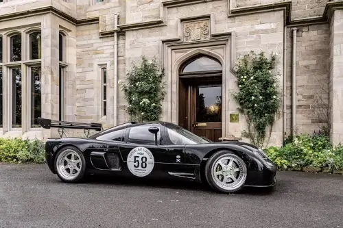 Black race car in front of Roxburghe Hotel, showcasing elegance and speed.