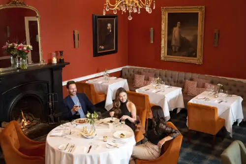 Three guests enjoy dinner at Sunlaws restaurant, surrounded by elegant decor.