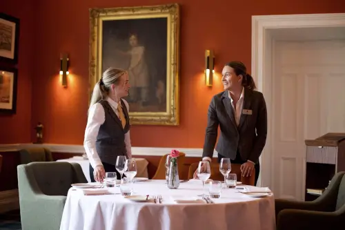 Staff at Roxburghe Hotel setting a dining table for an elegant meal.