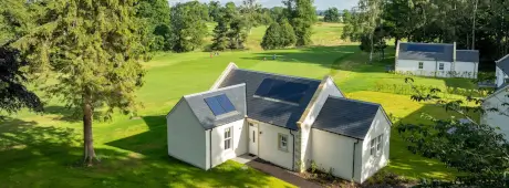 A serene view of the Roxburghe Hotel with a golf course and nearby trees.