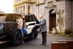 Guest arriving at Roxburghe Hotel welcomed by staff, luxury SUV in view.