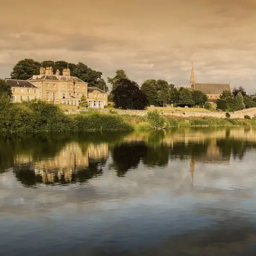 Scenic view of Roxburghe Hotel Golf & Spa beside the river, reflecting nature's beauty.