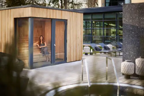 A woman in a sauna at Roxburghe Hotel Golf & Spa, surrounded by a relaxing spa area.