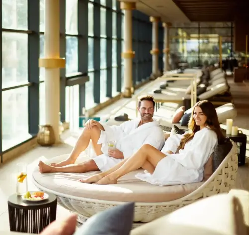 Couple relaxing in white robes at Roxburghe Hotel Spa, enjoying drinks and a peaceful ambiance.