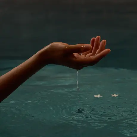 A hand drips water into a serene spa pool, enhancing relaxation at Roxburghe Hotel Golf & Spa Ltd.
