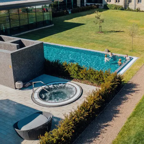 Outdoor swimming pool with guests at Roxburghe Hotel Golf & Spa, featuring a hot tub and lush gardens.