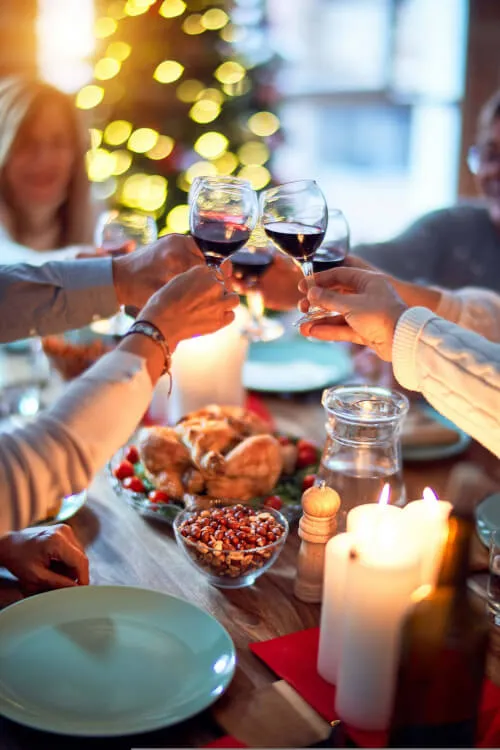 Friends toasting with wine glasses over a festive meal at Roxburghe Hotel Golf & Spa.